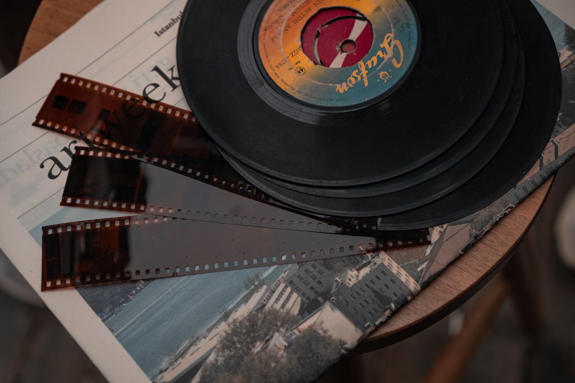 Stack of vintage vinyl records and film negatives on a warm wooden workshop table