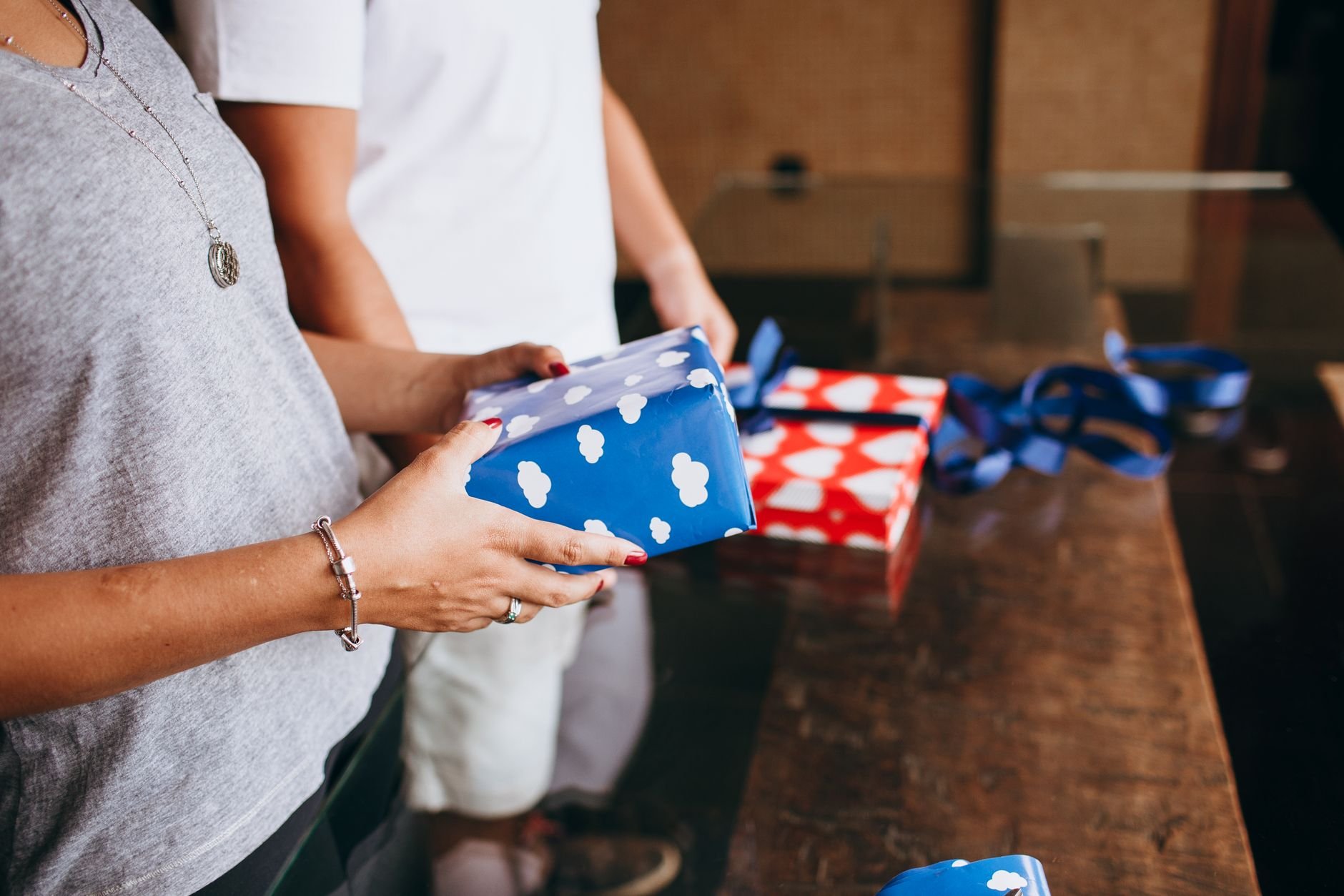 Close-up of people unwrapping handcrafted gifts together in a warm, festive setting