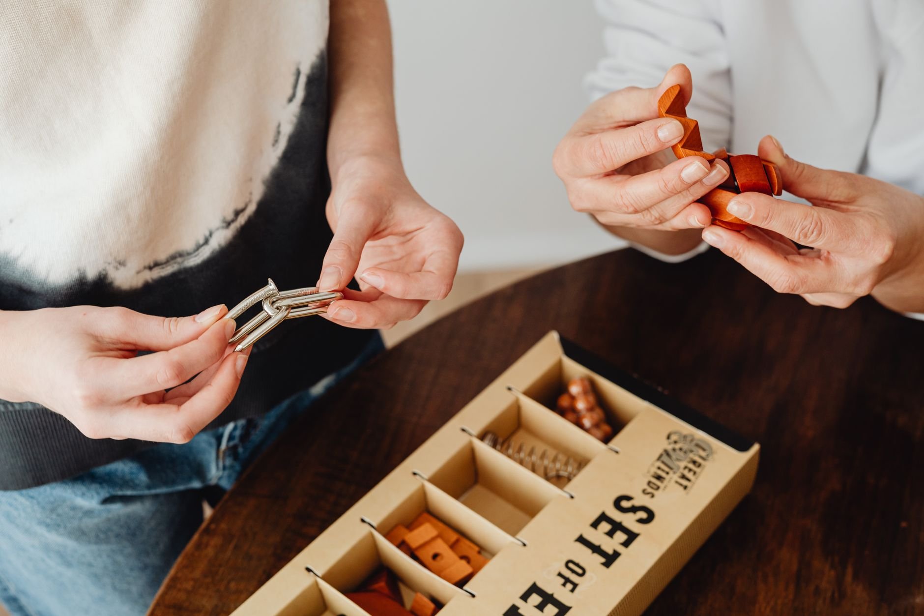 Close-up of hands engaging with wooden puzzle blocks on a warm workshop table